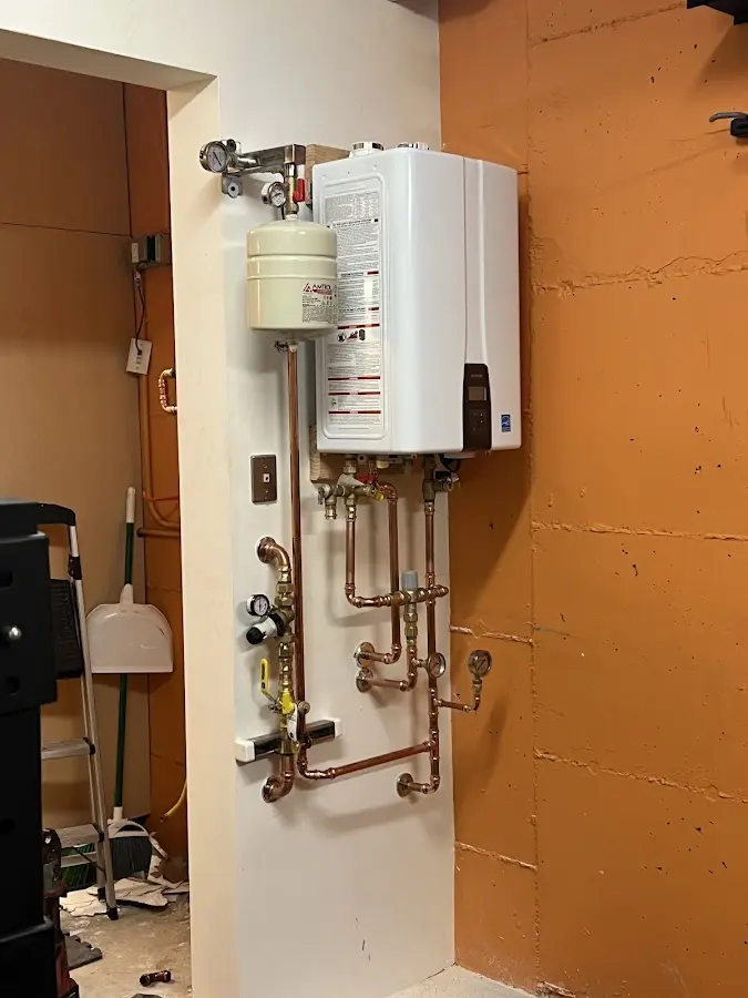 Plumbing technician inspecting water heater connections in Braintree Town